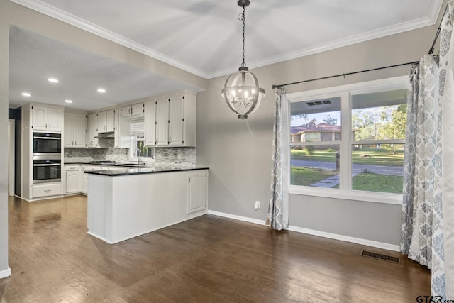 kitchen with backsplash, white cabinets, crown molding, hanging light fixtures, and dark hardwood / wood-style floors