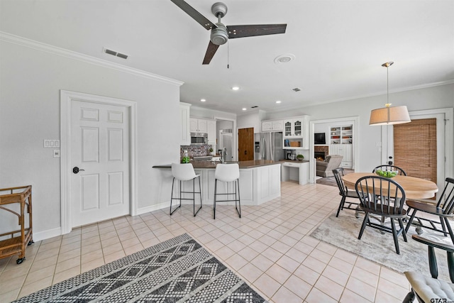 kitchen featuring stainless steel appliances, white cabinetry, light tile patterned floors, a breakfast bar, and kitchen peninsula