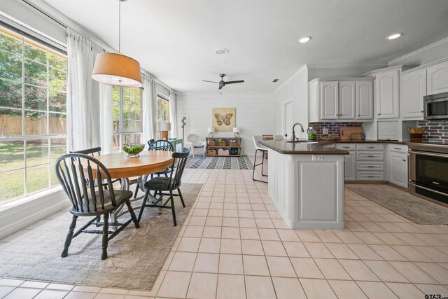 11213 Chasewood Dr, Tyler, TX 75703 - kitchen with dark countertops, appliances with stainless steel finishes, a sink, light tile patterned floors, and ornamental molding