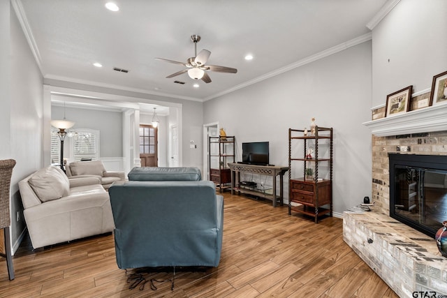 living room with ornamental molding, hardwood / wood-style floors, ceiling fan, and a fireplace