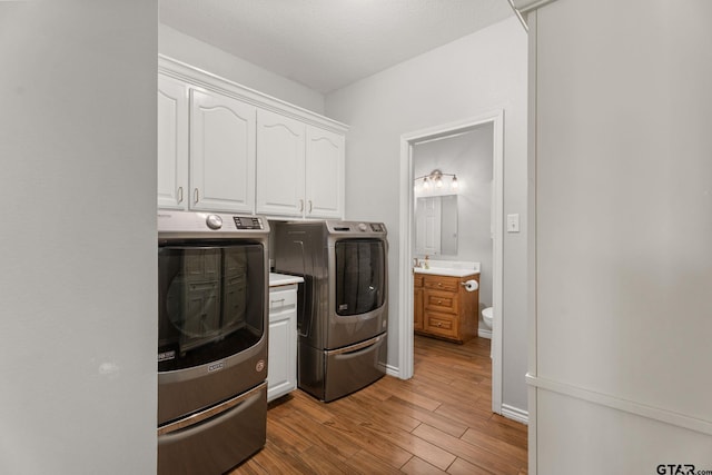 laundry room with cabinets, light hardwood / wood-style floors, and washer and dryer