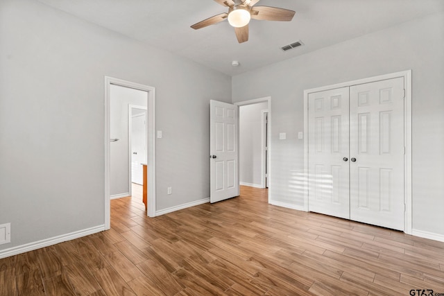 unfurnished bedroom with ceiling fan, light wood-type flooring, and a closet