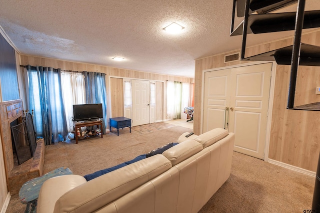 carpeted living room featuring wood walls, a fireplace, and a textured ceiling