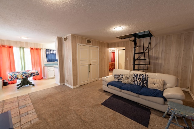 living room with carpet flooring, wooden walls, and a textured ceiling