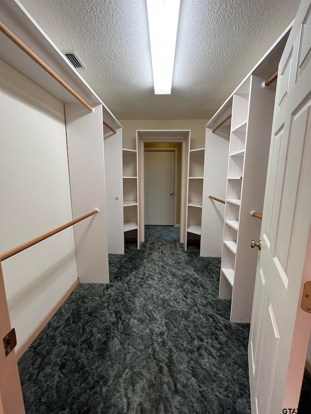 walk in closet with dark carpet