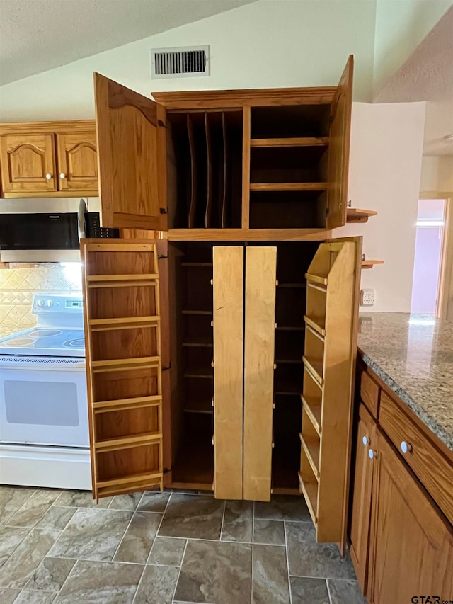 kitchen with white range oven, light stone countertops, and vaulted ceiling