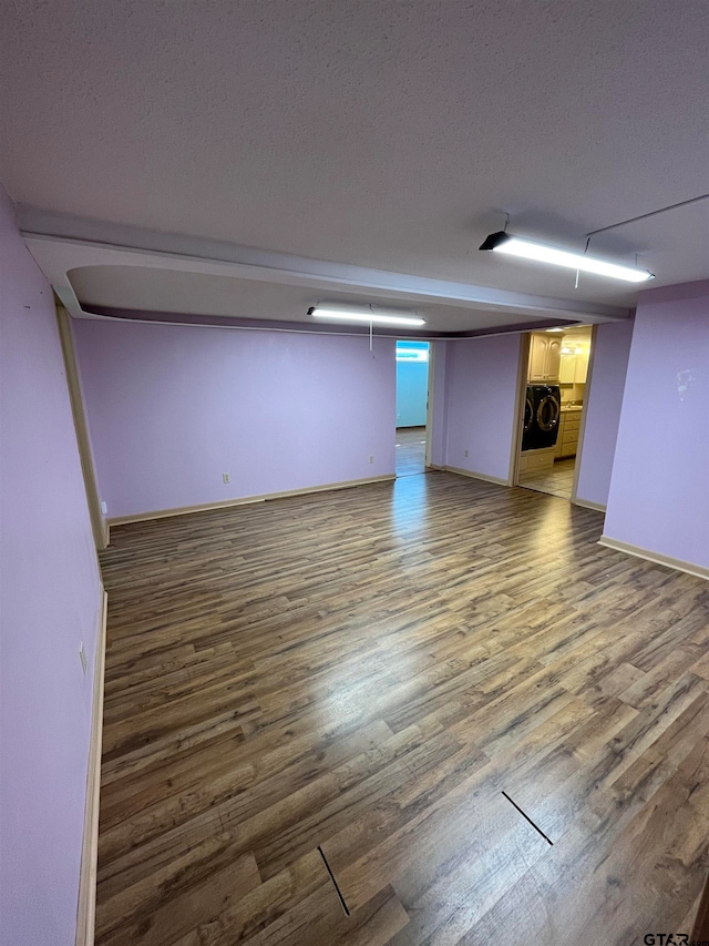 basement featuring hardwood / wood-style flooring, a textured ceiling, and washer / clothes dryer