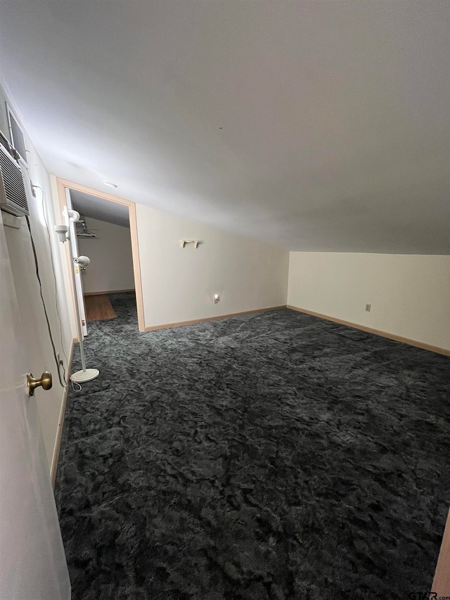 bonus room with lofted ceiling and dark carpet