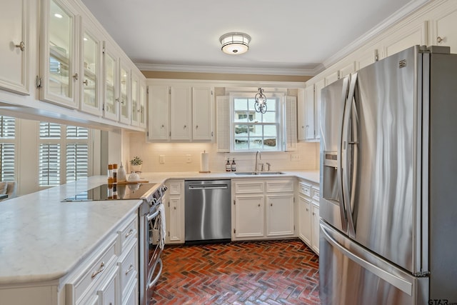 kitchen featuring appliances with stainless steel finishes, white cabinetry, sink, decorative backsplash, and crown molding