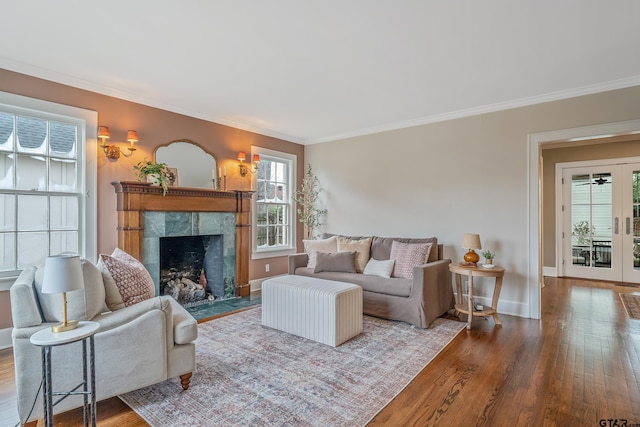 living room featuring hardwood / wood-style floors, a premium fireplace, ornamental molding, and french doors