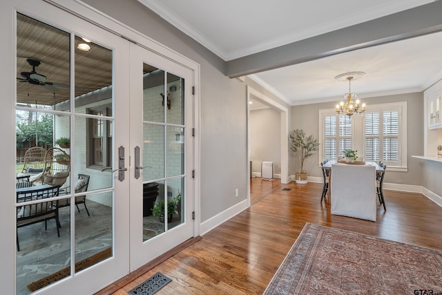 dining area featuring ornamental molding, wood-type flooring, ceiling fan with notable chandelier, and french doors