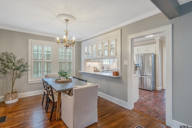 dining room with dark hardwood / wood-style flooring, sink, crown molding, and an inviting chandelier