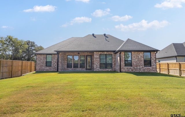 back of house featuring brick siding, a fenced backyard, and a lawn