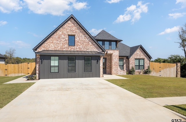 view of front facade with a gate, driveway, a front lawn, board and batten siding, and brick siding