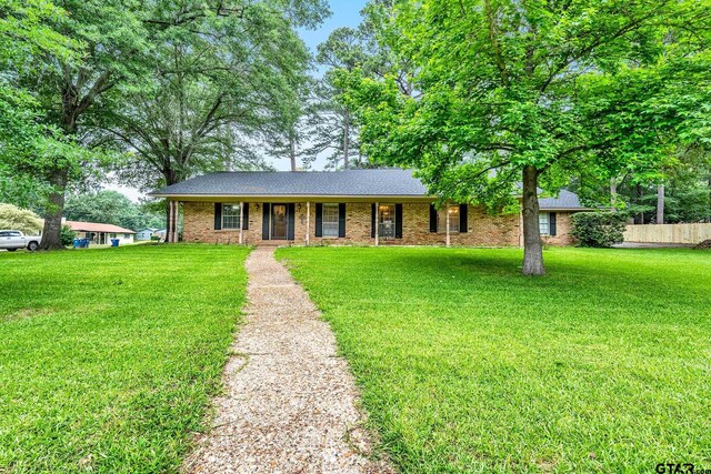 ranch-style home featuring a front lawn, a porch, fence, and brick siding