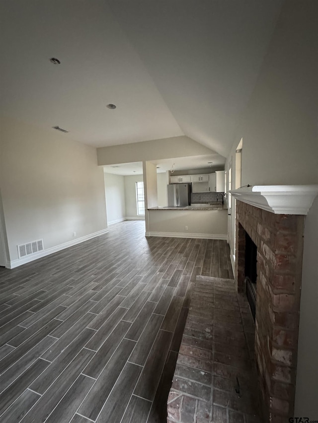 unfurnished living room featuring vaulted ceiling and a fireplace