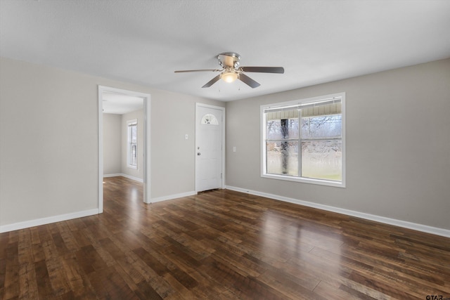 unfurnished room with ceiling fan, baseboards, and dark wood-type flooring