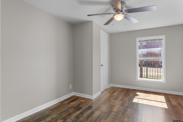 spare room with dark wood-style floors, baseboards, and a ceiling fan