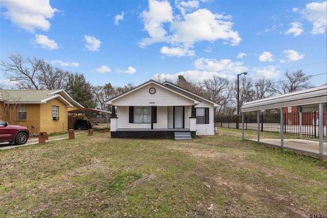 bungalow-style home featuring a detached carport, covered porch, fence, and a front lawn