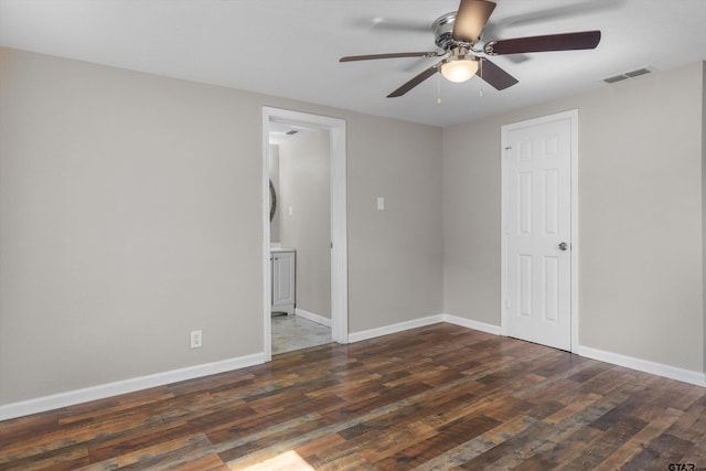 empty room featuring dark wood-type flooring, visible vents, and baseboards