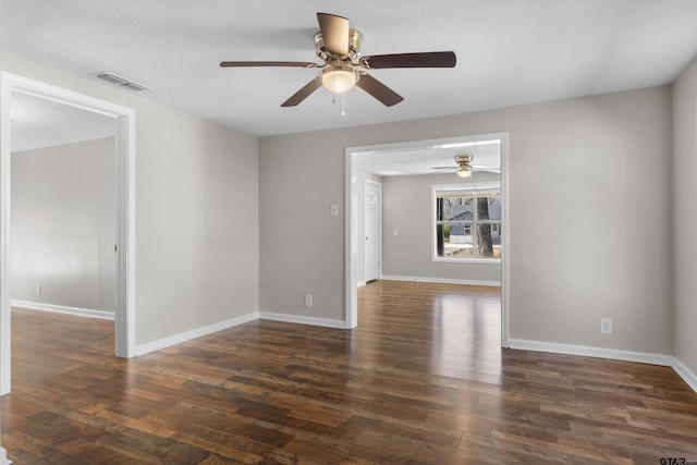 unfurnished room with baseboards, visible vents, and dark wood-style flooring