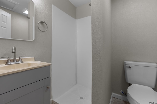 full bathroom featuring toilet, a textured wall, and vanity