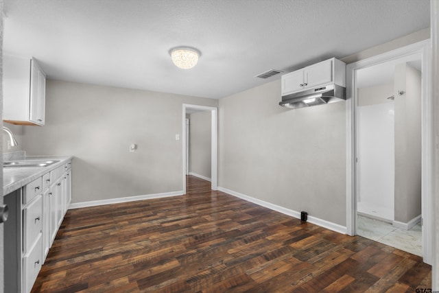 kitchen with dark wood-style flooring, light countertops, visible vents, white cabinetry, and a sink