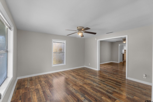 unfurnished room featuring a ceiling fan, visible vents, dark wood finished floors, and baseboards