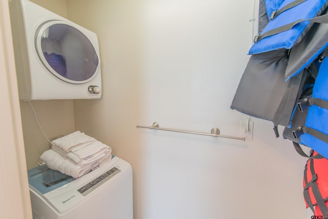 clothes washing area with stacked washing maching and dryer