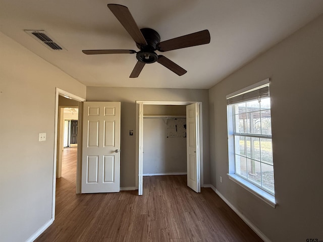 unfurnished bedroom featuring a closet, wood finished floors, visible vents, and baseboards