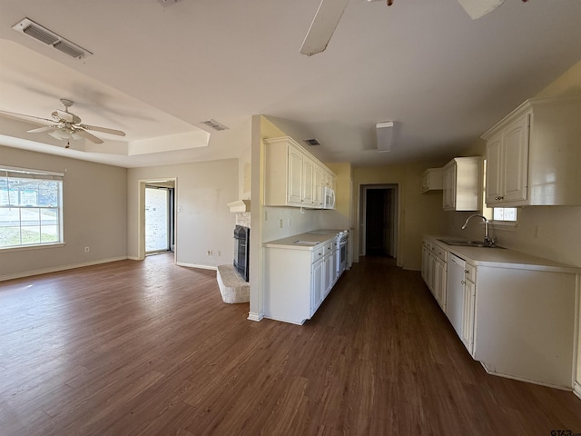 kitchen with a ceiling fan, white cabinets, visible vents, and a fireplace