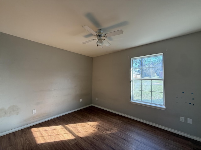 spare room with dark wood-style floors, a ceiling fan, and baseboards