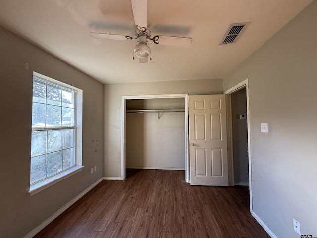 unfurnished bedroom with a ceiling fan, visible vents, baseboards, a closet, and dark wood finished floors