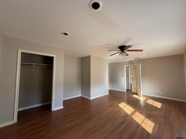 unfurnished bedroom featuring dark wood-type flooring, a closet, ceiling fan, and baseboards