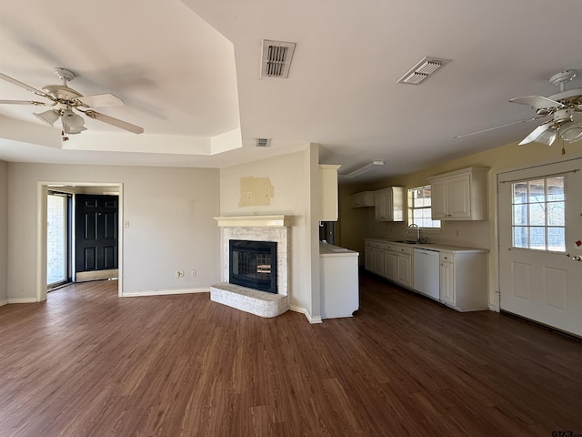 unfurnished living room with ceiling fan, visible vents, dark wood-type flooring, and a sink