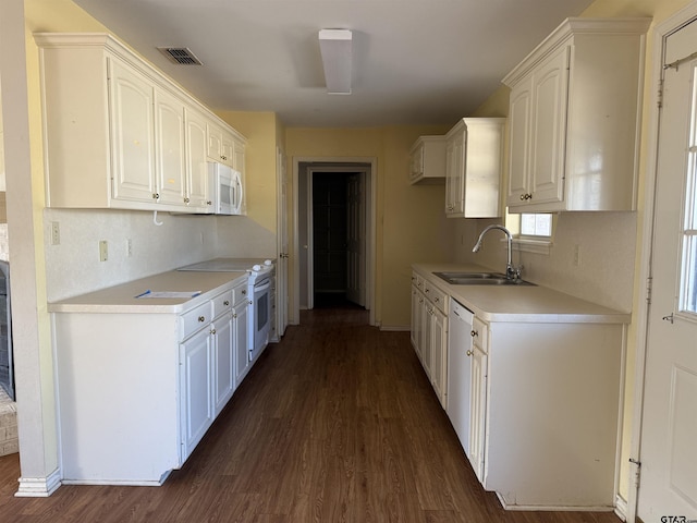 kitchen with dark wood-style flooring, light countertops, white cabinetry, a sink, and white appliances