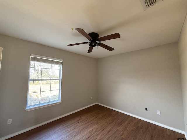 empty room featuring a ceiling fan, dark wood finished floors, visible vents, and baseboards