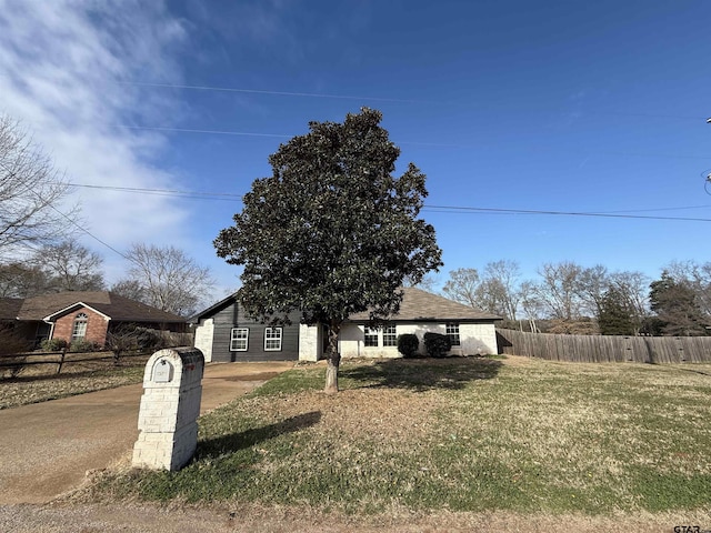 view of front of home featuring concrete driveway, fence, and a front lawn