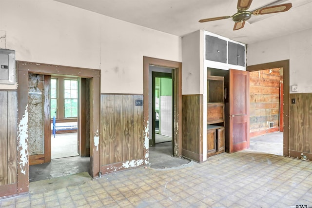 unfurnished room featuring ceiling fan, wood walls, and a wainscoted wall