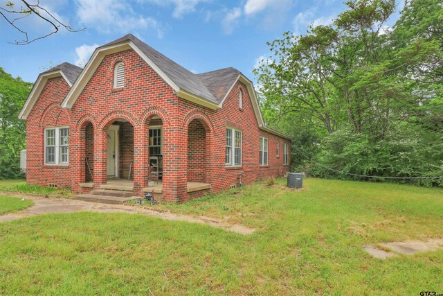 view of front of property with a front lawn, brick siding, and cooling unit