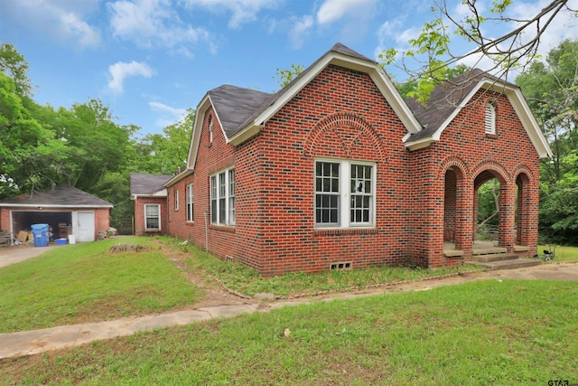 view of front of property featuring an outdoor structure, brick siding, a detached garage, and a front lawn