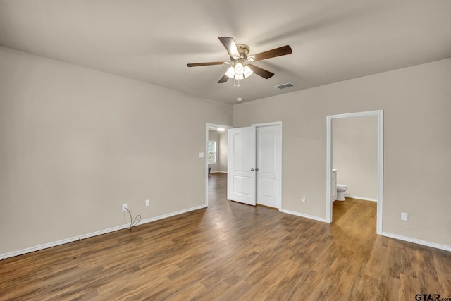 unfurnished bedroom featuring hardwood / wood-style flooring, ensuite bathroom, and ceiling fan