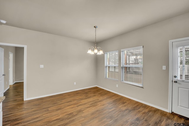 spare room with dark hardwood / wood-style flooring and an inviting chandelier