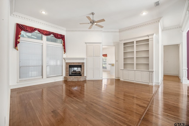 unfurnished living room featuring a fireplace, a wealth of natural light, wood-type flooring, and crown molding