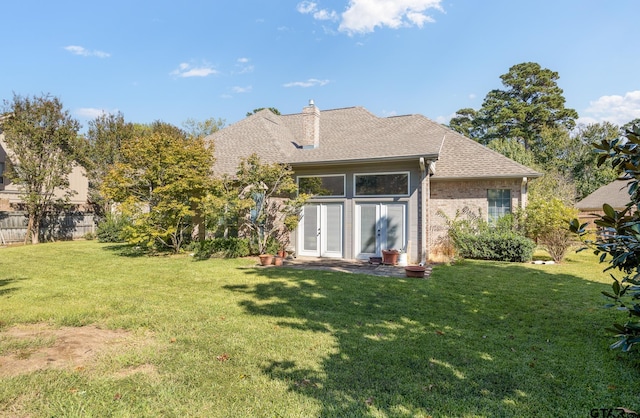 rear view of property with french doors and a yard