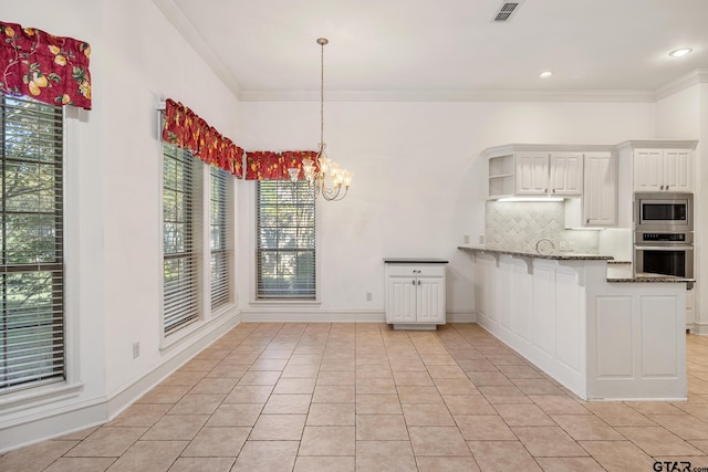 kitchen with stainless steel appliances, kitchen peninsula, dark stone countertops, a healthy amount of sunlight, and white cabinets