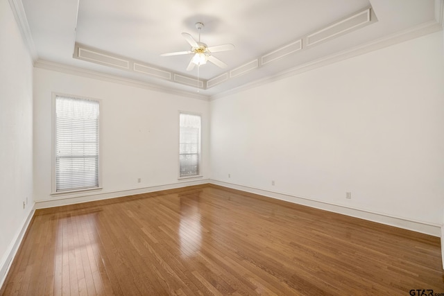 spare room with crown molding, hardwood / wood-style floors, ceiling fan, and a raised ceiling