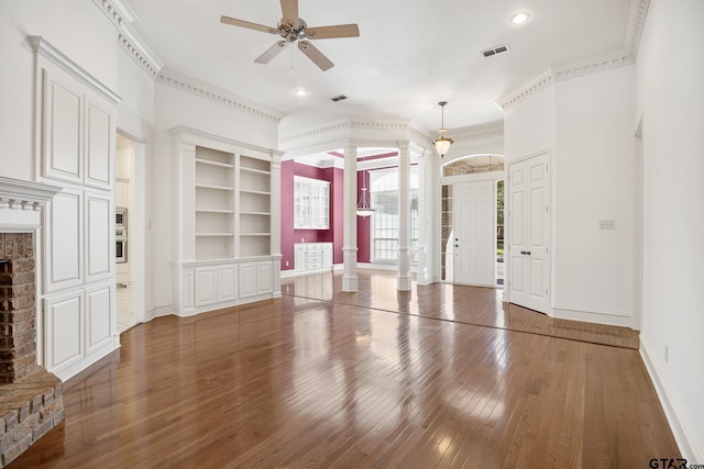 unfurnished living room with dark wood-type flooring, decorative columns, ornamental molding, and ceiling fan