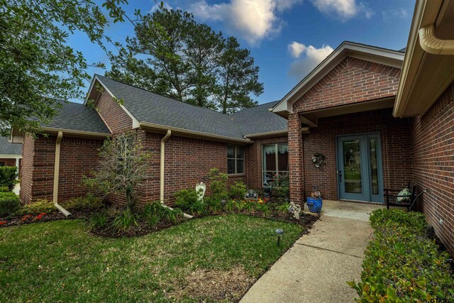 view of exterior entry with a yard