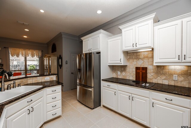 kitchen with white cabinetry, stainless steel refrigerator with ice dispenser, sink, black electric stovetop, and dark stone countertops